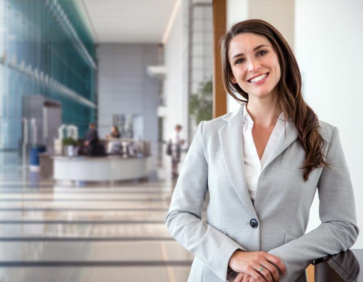 A woman standing in an office building and smiling.